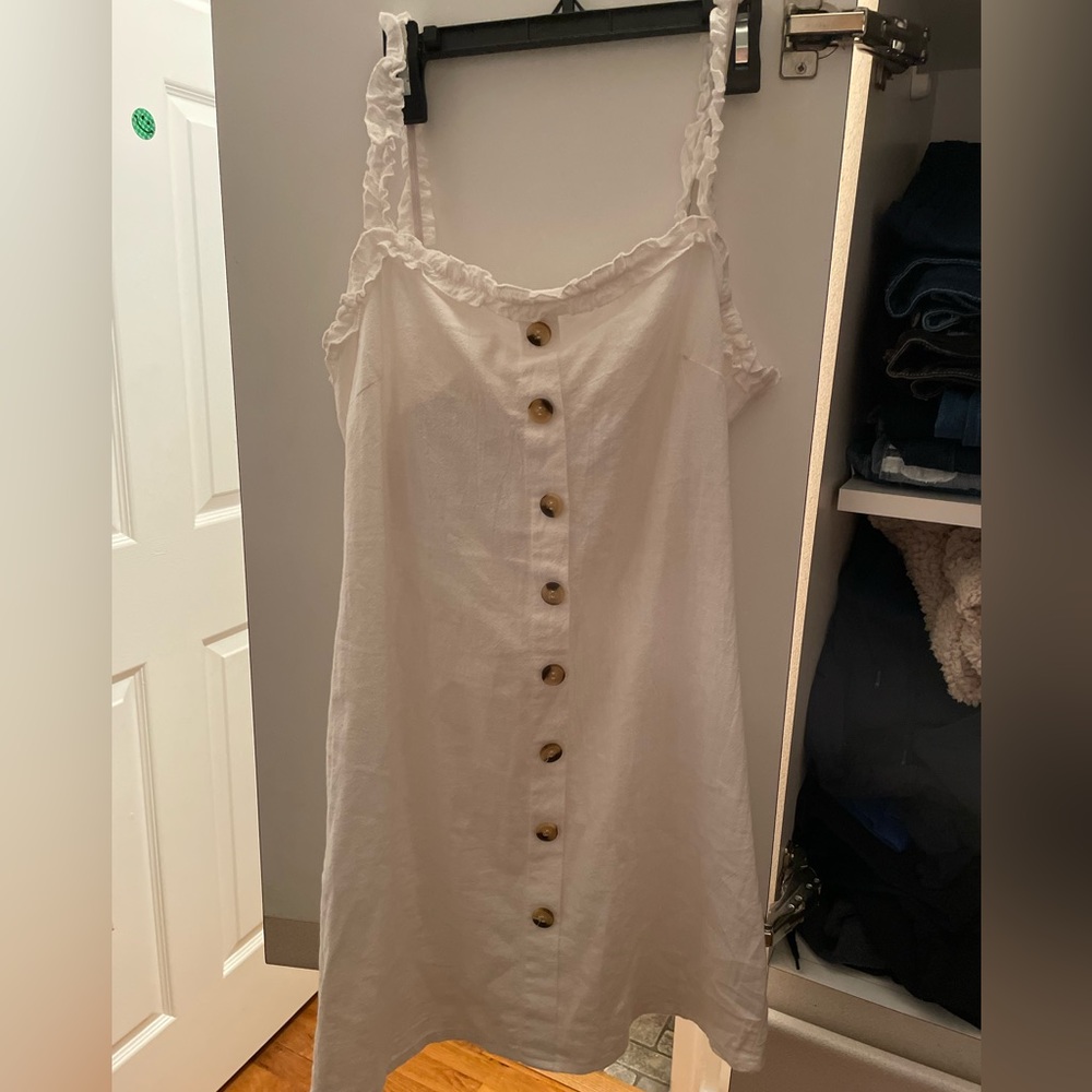 White mini dress with buttons down the front and a tie back with opening